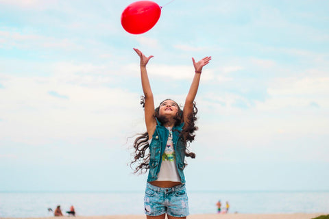 Young girl on the beach playing with a balloon