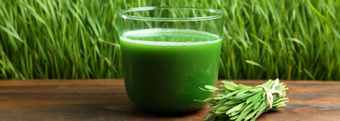 Glass of green juice on a table with grass in the background