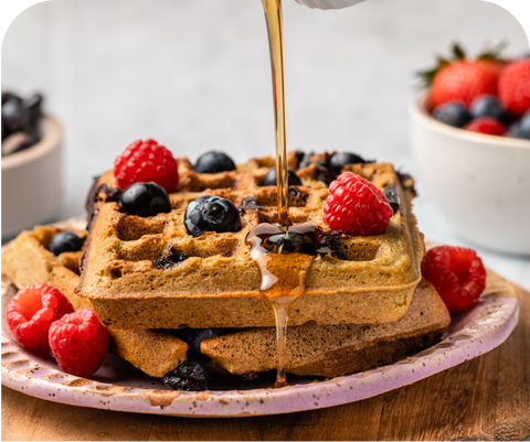 Waffles made with Amazing Grass on a plate with berries and syrup