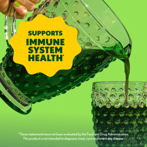 Green liquid being poured from a bottle into a glass with a yellow label stating 'Supports Immune System Health' on a green background.