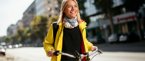 Woman wearing a yellow coat smiling while riding a bike down a city street